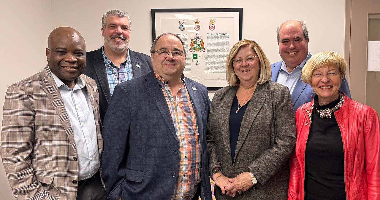 Groupe des membres nommés dans la description ci-dessous regardant la caméra